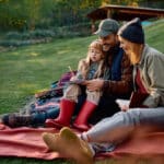 Parents and daughter relaxing outdoors with a notebook, representing the kind of everyday family finances affected by modified adjusted gross income.