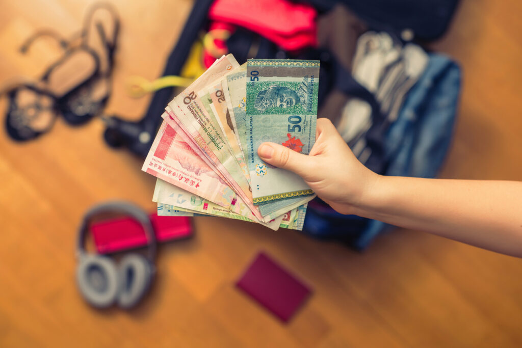 Female hands holding Asian currency and a foreign passport while preparing taxes as an expat.