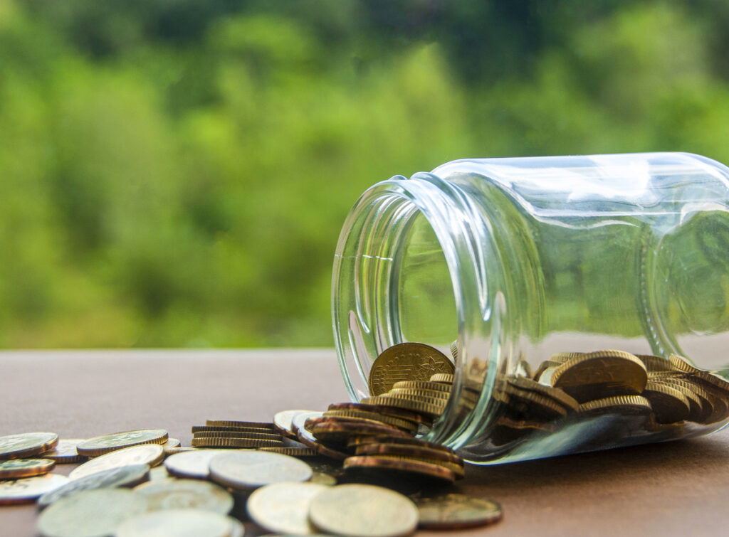 Gold coins on a wooden table with a nature background, related to delinquent FBAR submission procedures and foreign account reporting.