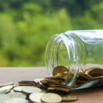 Gold coins on a wooden table with a nature background, related to delinquent FBAR submission procedures and foreign account reporting.