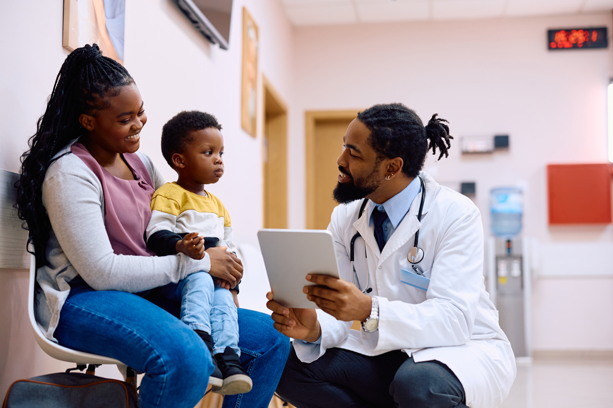 Smiling doctor speaking with a mother and son in a clinic—offering a glimpse into everyday healthcare in Canada.