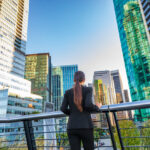 Businesswoman overlooking the Vancouver skyline, thinking about starting a business in Canada.