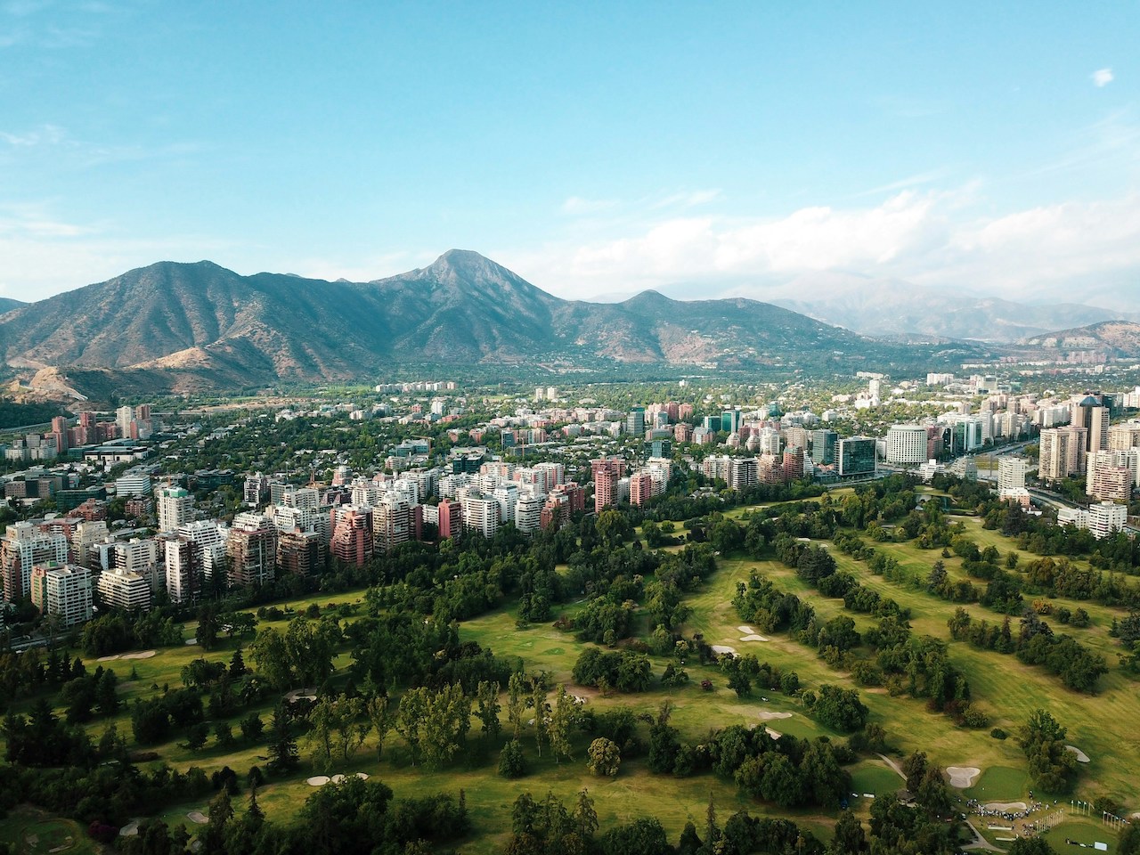 City skyline with a golf course and mountains, capturing the lifestyle enjoyed by many Americans living in Chile.
