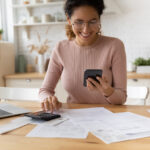Young woman smiling after a successful mobile transaction—embracing modern banking, finances, and taxes in the UK.