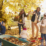 Children and parents gathering autumn leaves together, capturing the everyday joy of raising a family in Canada.