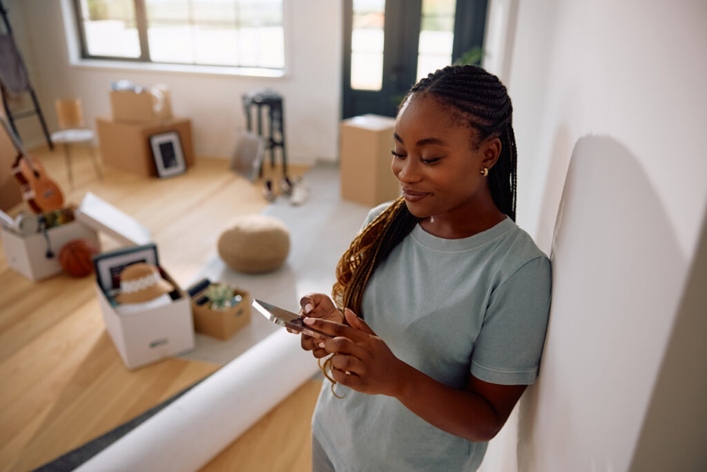 Relaxed and happy woman checks her phone after moving, embracing her new life in Canada.