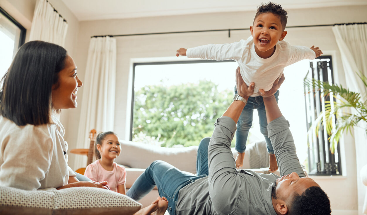 Young family playing on the living room floor, enjoying the everyday moments of raising a family UK style.