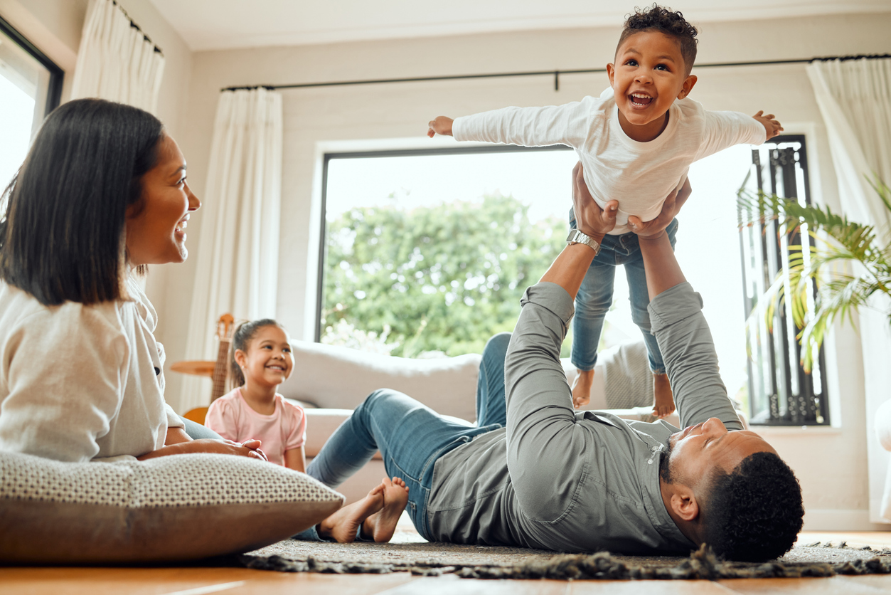 Young family playing on the living room floor, enjoying the everyday moments of raising a family UK style.