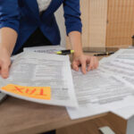 A professional woman is sorting through tax documents, highlighting her role in tax preparation and analysis in a contemporary office setting.
