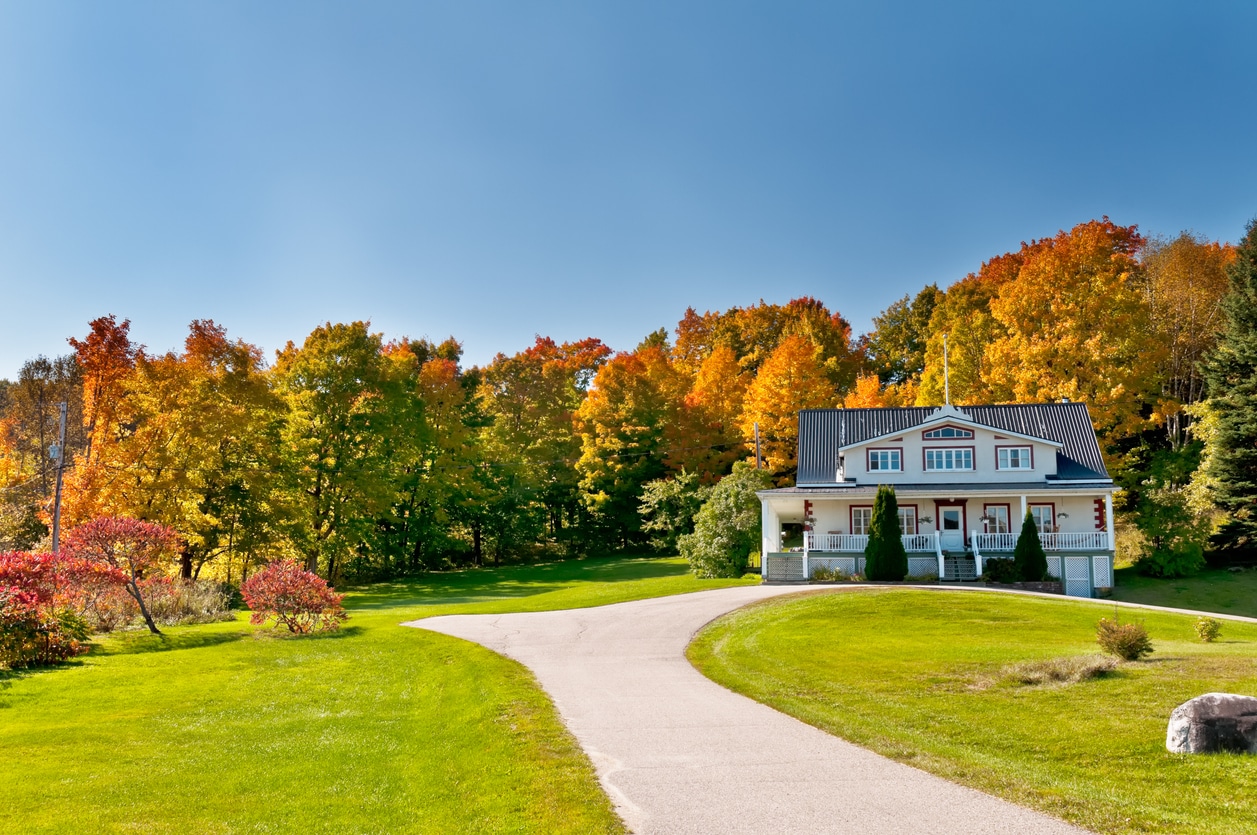 Charming house framed by autumn trees, capturing the dream many have when buying property in Canada.