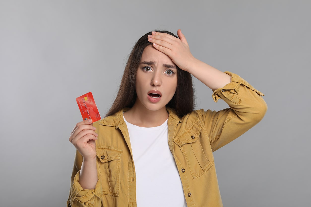Woman reacting with shock while holding a credit card, capturing the confusion around the question: is scammed money tax deductible.