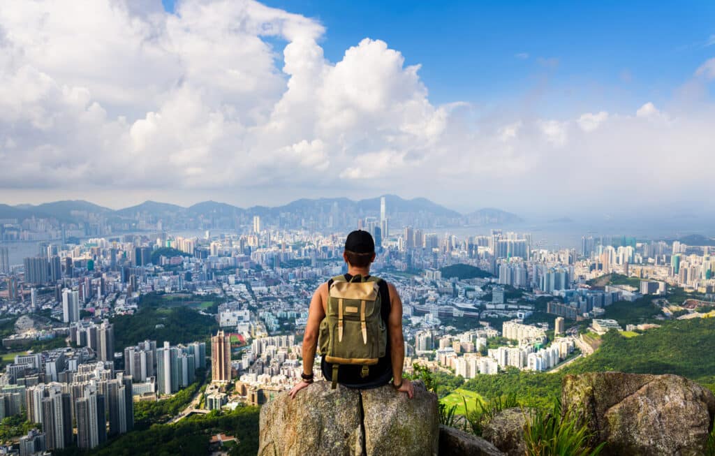 Man looking out over a sprawling city view from the mountains, capturing the scale and energy of life for Americans living in China.