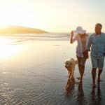 Couple relaxing on the beach with their dog, reflecting the peace of mind that comes with having health insurance for US expats.