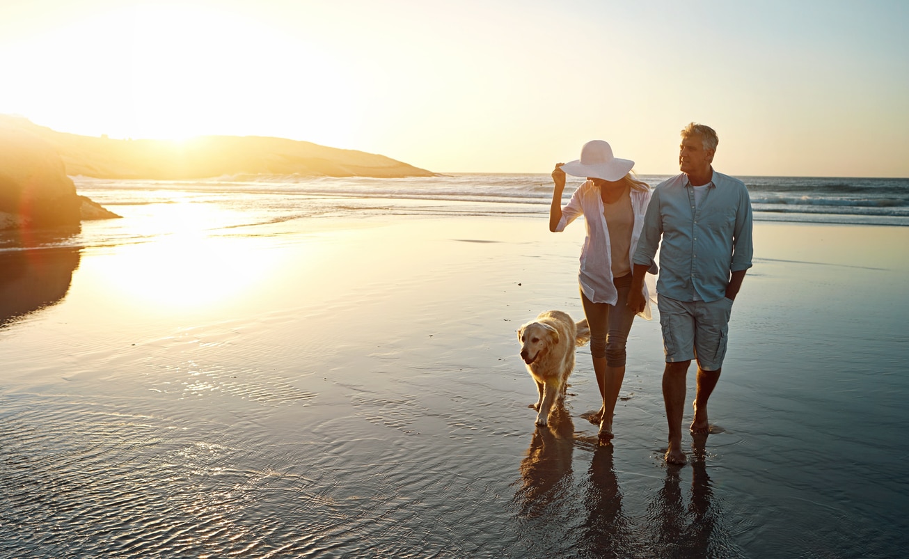 Couple relaxing on the beach with their dog, reflecting the peace of mind that comes with having health insurance for US expats.