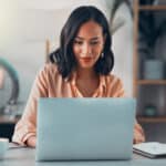 Woman working alone in an office on her laptop, reviewing figures related to foreign tax credit calculation.
