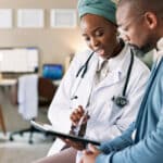 Doctor showing a patient information on a tablet during a clinic consultation, reflecting access to care through health insurance Germany.