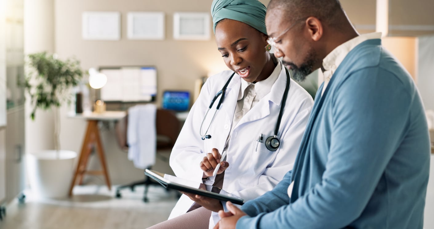 Doctor showing a patient information on a tablet during a clinic consultation, reflecting access to care through health insurance Germany.