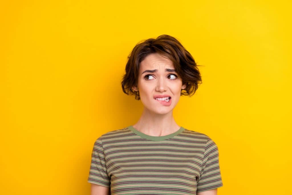 Unsure young woman biting her lip, capturing the feeling of realizing you may need to file Form 1040-X.