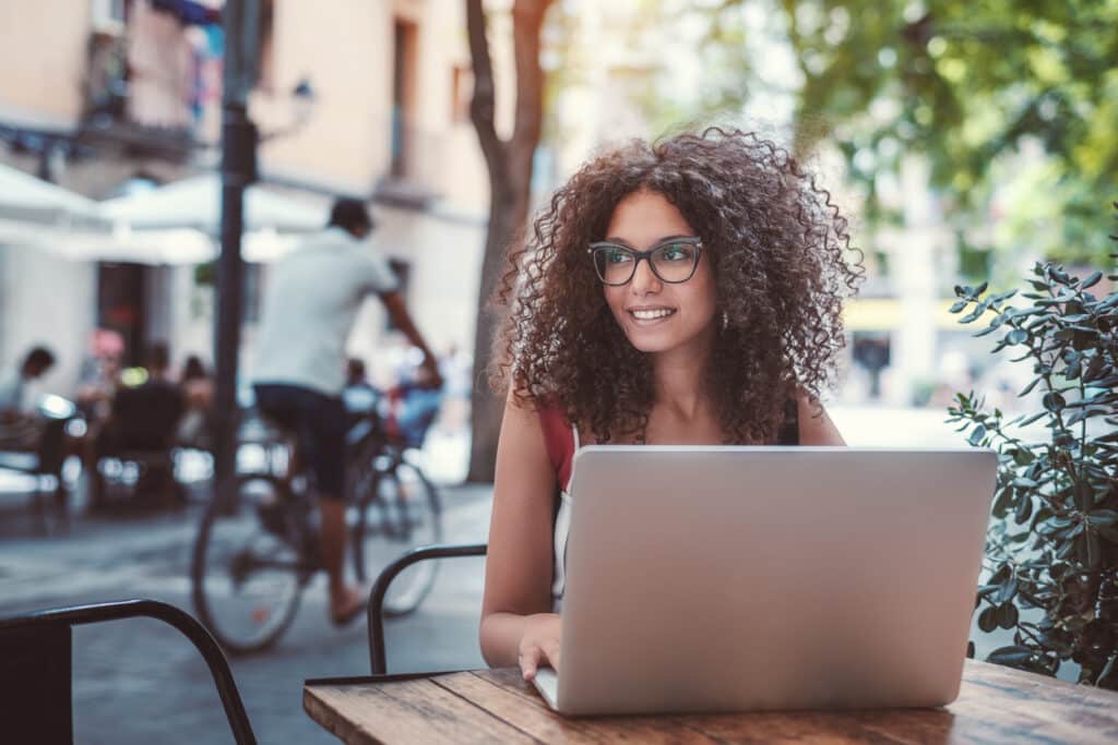 Freelancer working on a laptop at an outdoor café, representing the income planning decisions affected by marginal tax rates.