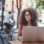 Freelancer working on a laptop at an outdoor café, representing the income planning decisions affected by marginal tax rates.