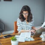 Worried woman reviewing household bills and financial paperwork, reflecting the stress that can come before qualifying for an automatic exemption from penalty.