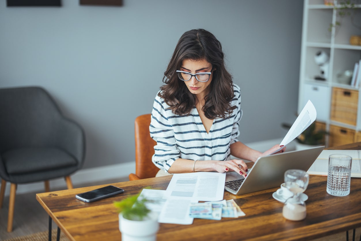 Worried woman reviewing household bills and financial paperwork, reflecting the stress that can come before qualifying for an automatic exemption from penalty.