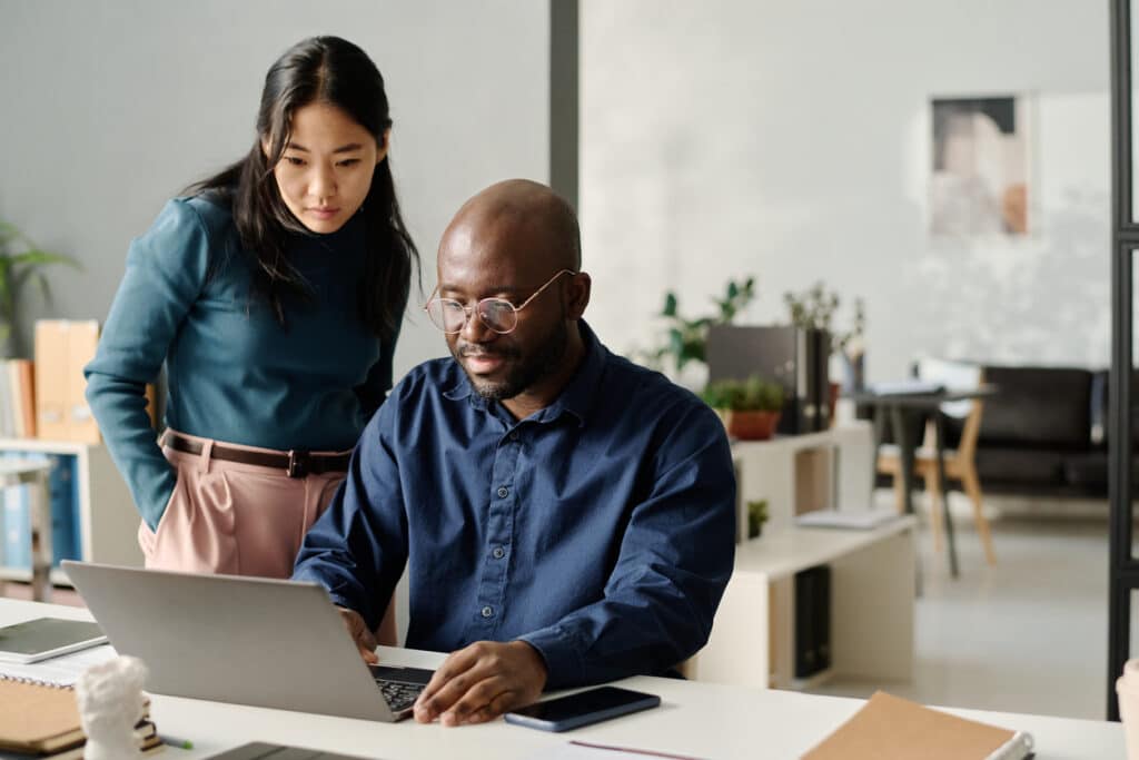 Two coworkers reviewing a laptop presentation, reflecting the financial planning and investment income issues connected to Form 8960.