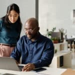 Two coworkers reviewing a laptop presentation, reflecting the financial planning and investment income issues connected to Form 8960.
